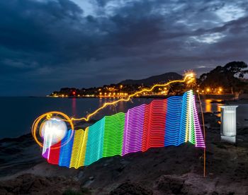 Multi colored umbrella on beach against sky at night