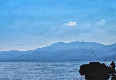 Scenic view of sea and mountains against blue sky