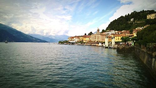 Residential district by lake como against cloudy sky
