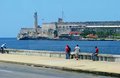 People at sea shore against clear sky