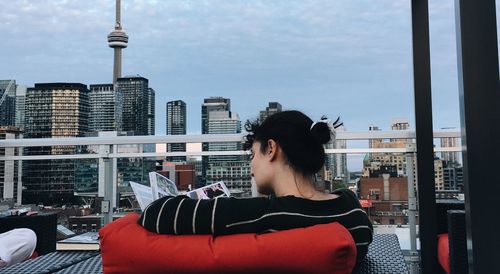 Mid adult woman against modern buildings in city against sky