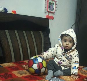 Portrait of cute girl with ball on floor at home