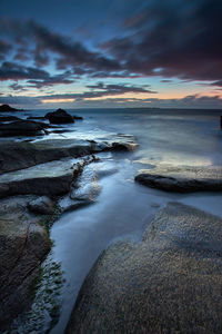 View of calm beach against cloudy sky