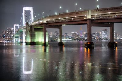 Illuminated bridge over river against sky in city at night