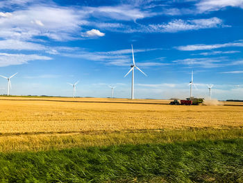 Windmills on field against sky