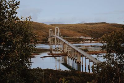 Footbridge over river against cloudy sky