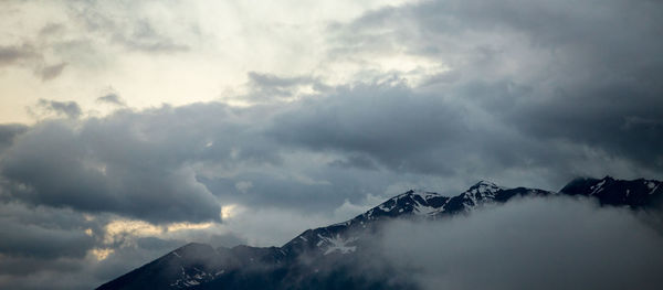 Low angle view of mountains against cloudy sky during sunset