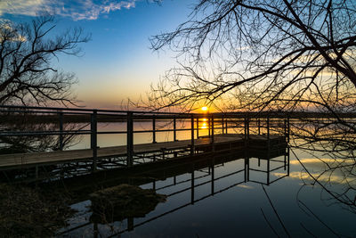 Silhouette bridge over river against sky during sunset