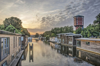 Canal amidst buildings against sky during sunset