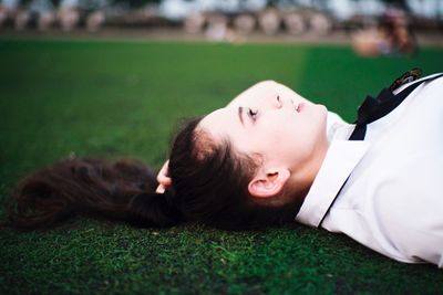 Side view of woman lying on grass