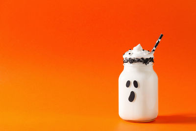 Close-up of coffee cup against orange background