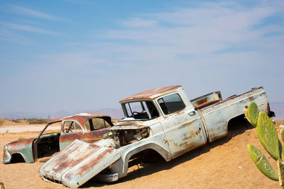 Abandoned car on field against sky