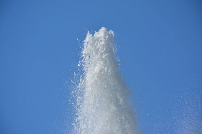 Low angle view of water splashing against blue sky