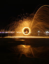 Man spinning wire wool against sky at night