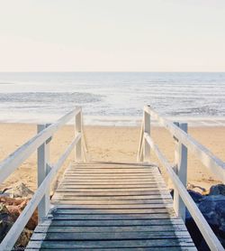 Boardwalk on beach against clear sky