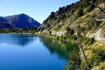 Scenic view of lake and mountains against clear blue sky