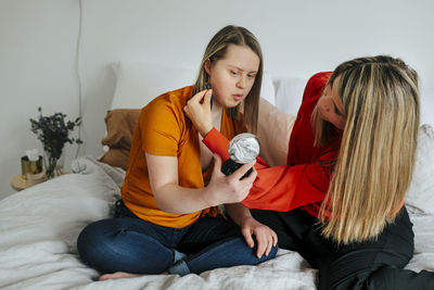 Sisters having make-up on bed