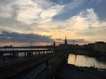 Bridge over river against cloudy sky during sunset