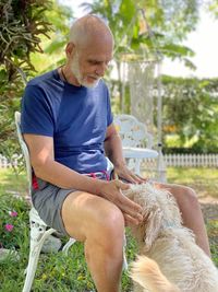 Man playing with dog while sitting in yard