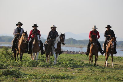 Men wearing costumes sitting on horses against sky