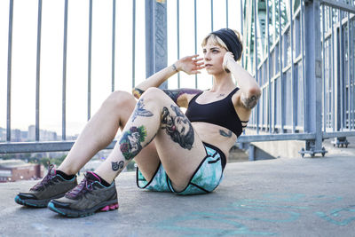 Young tattooed woman doing sit ups on bridge with sunset behind