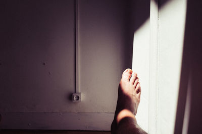 Low section of man against wall at home