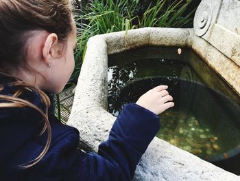 High angle view of girl throwing coin in wishing well