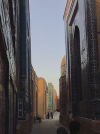 People on street amidst buildings in city against sky