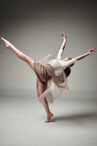 Young woman dancing against gray background