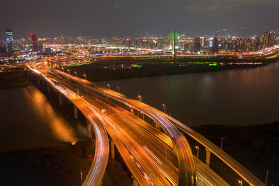 High angle view of illuminated bridge over river in city at night