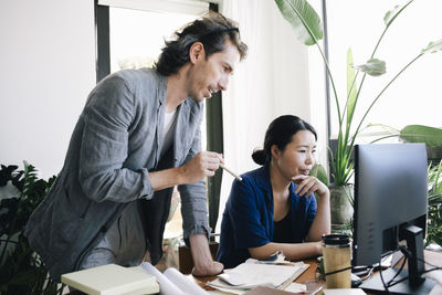 Male architect discussing with female colleague using computer at home office