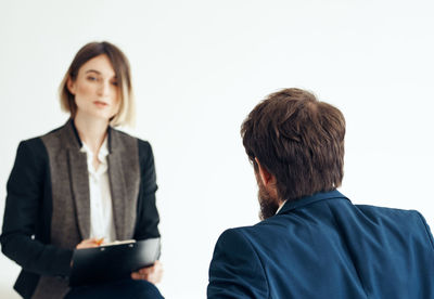 Portrait of smiling businesswoman standing against white background