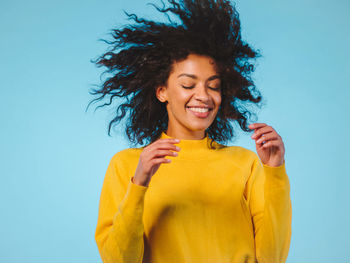 Happy young woman with tousled hair against blue background
