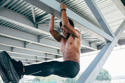 Young man exercising while hanging from ceiling