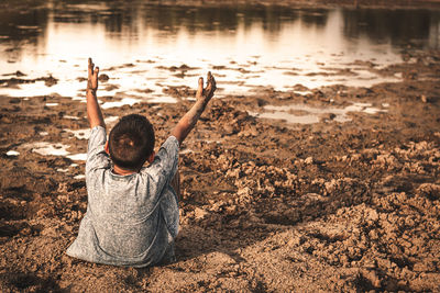 Rear view of man sitting on rock at beach