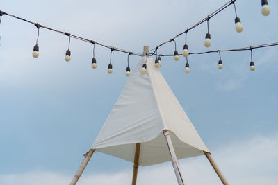 Low angle view of light bulbs hanging against sky