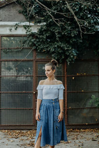 Full length of woman standing by fence against trees