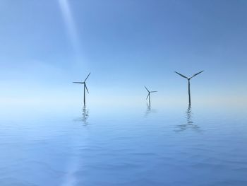 Wind turbines in water against sky