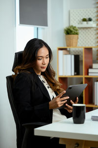 Portrait of young woman using laptop while sitting at home