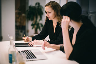 Young woman using mobile phone while sitting on table