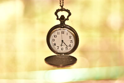 Close-up of pocket watch hanging against illuminated lights