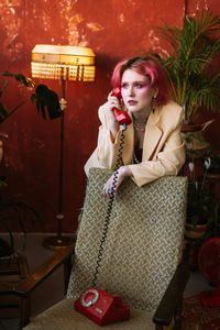 Young fashion stylish woman posing with retro phone, bright make up and colored hair
