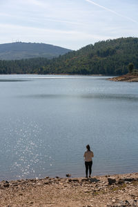 Caucasian girl looking at the lake water of apartadura dam with mountains and trees