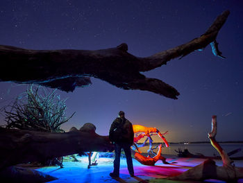Man standing on shore against clear sky at night