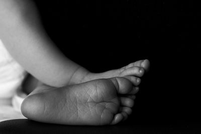 Low section of baby girl over black background