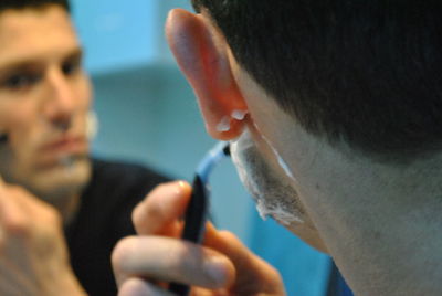 Cropped image of man shaving with reflection on mirror
