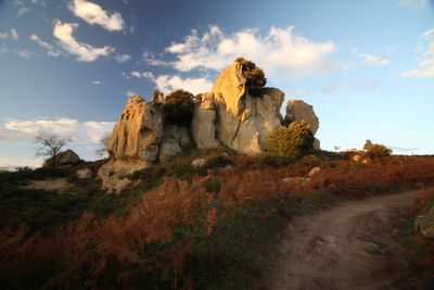 Rock formations on landscape against cloudy sky