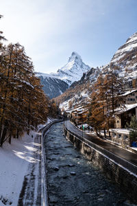 Snow covered road by mountain against sky