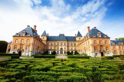 Buildings in garden against cloudy sky