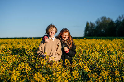 Rear view of woman standing amidst oilseed rape field against clear sky